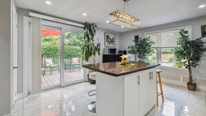 Une cuisine moderne dotée d’un îlot central, de meubles blancs et d’une grande fenêtre offrant une vue sur l’extérieur.