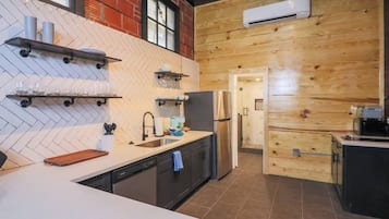 Uma cozinha moderna com revestimento de azulejos em padrão herringbone, painéis de parede em madeira, geladeira de aço inoxidável e lava-louças embutida.