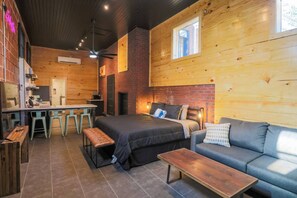 A cozy room with a bed, a sofa, a table, and a kitchen area. - Restored Historic Loft - 3 Mins to the Beach (Galveston)
