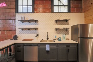 A kitchen with a herringbone tile backsplash, stainless steel appliances, and wooden accents. - Restored Historic Loft - 3 Mins to the Beach (Galveston)