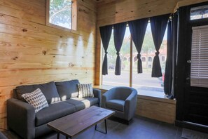 A wooden interior with a sofa, armchair, and a window with curtains. - Restored Historic Loft - 3 Mins to the Beach (Galveston)