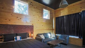 A log cabin room with a bed, sofa, armchair, and a fireplace. - Restored Historic Loft - 3 Mins to the Beach (Galveston)
