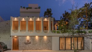 Un hotel moderno con fachada plana, varios balcones con listones de madera y un logotipo destacado en la entrada.