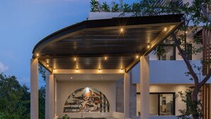 Un área de cocina exterior moderna con techo curvo, asientos integrados e iluminación ambiental.