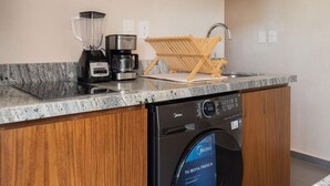 Una cocina compacta con lavavajillas integrado, cafetera y microondas.