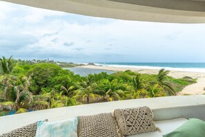 A balcony with a view of a beach and palm trees. - Turtle Seaview   (Santa Maria Colotepec)