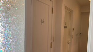 A hallway with three doors, each marked with a restroom symbol.