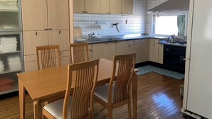 A kitchen with wooden cabinets, a dining table with chairs, and a refrigerator.