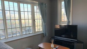A living room with a sofa, a coffee table, a TV, and a window with curtains.