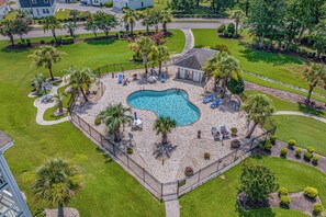 Vista aérea de una propiedad residencial con piscina, rodeada de palmeras y un patio empedrado.