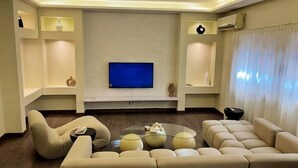 A modern living room with a large flat-screen TV, beige sofas, and a glass coffee table. - Nile Haven Zamalek Island 3BR (Cairo Governorate)