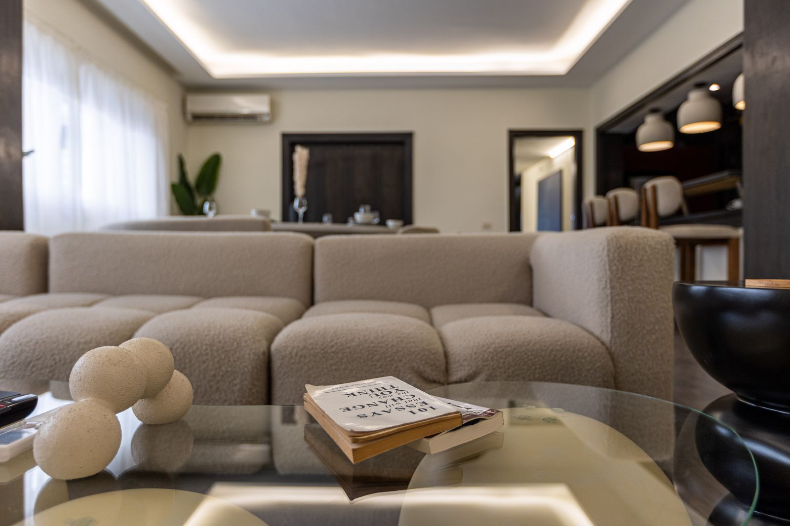 Ein modernes Wohnzimmer mit einem Ecksofa, einem Glastisch und einer schwarzen Schale.