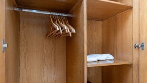 A wooden wardrobe with a hanging rod and a shelf. - Nile Haven Zamalek Island 3BR (Cairo Governorate)