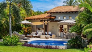A resort with a swimming pool, lounge chairs, and umbrellas.
