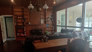Un salon chaleureux avec une cheminée en briques, un canapé en cuir, une table basse en bois et une bibliothèque.
