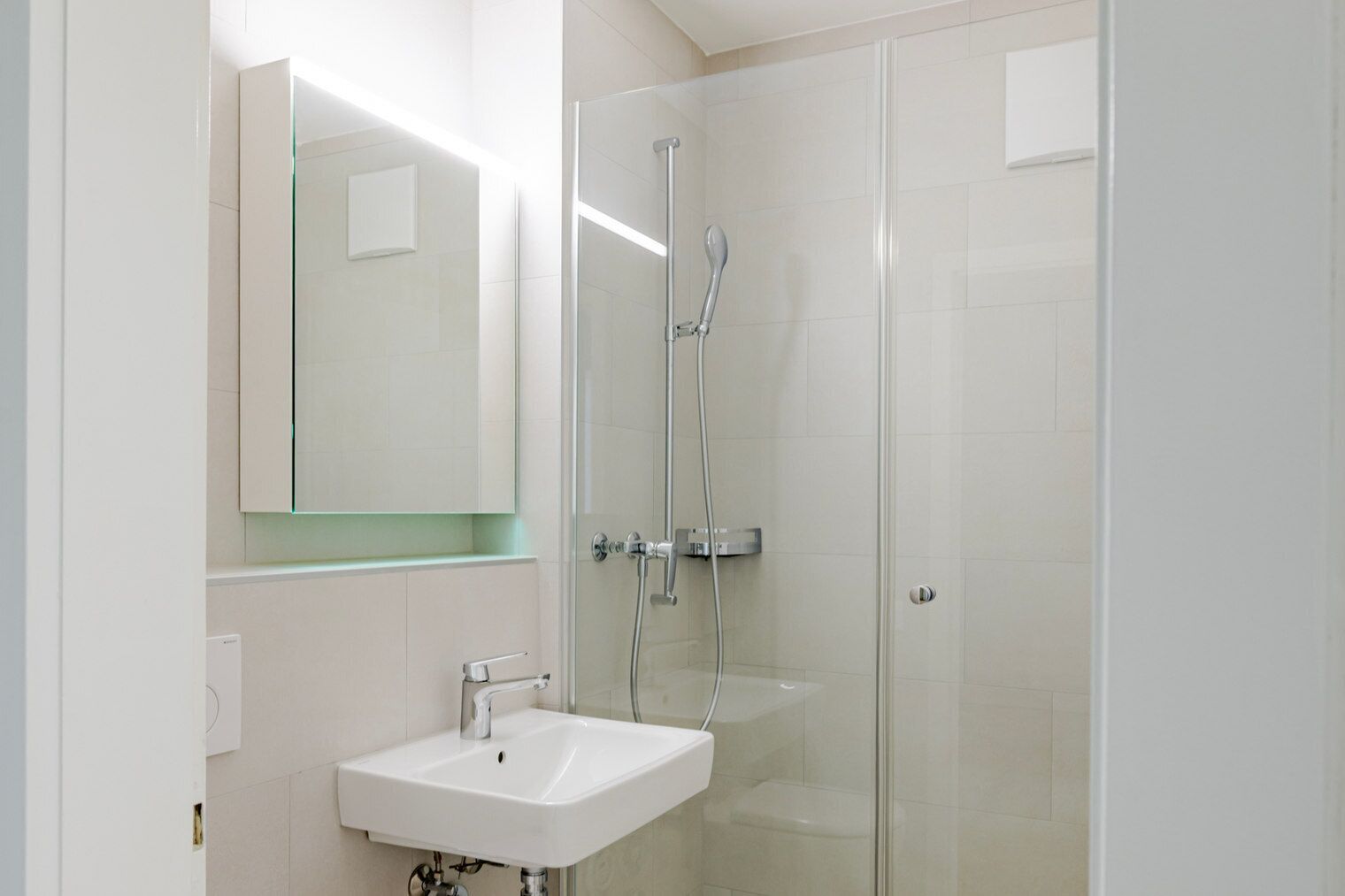 A modern bathroom with a glass shower enclosure, a white sink, and a large mirror.