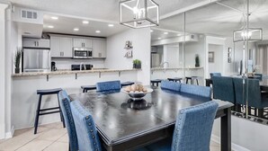 A modern kitchen with white cabinets, a stainless steel refrigerator, and a microwave.