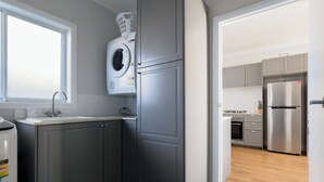Eine moderne Küche mit grauen Schränken, einer integrierten Waschmaschine und einem Edelstahl-Kühlschrank.