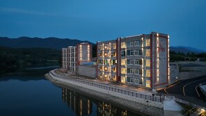 Un hotel moderno de varios pisos con vista al agua, que cuenta con una entrada destacada y una fachada bien iluminada.