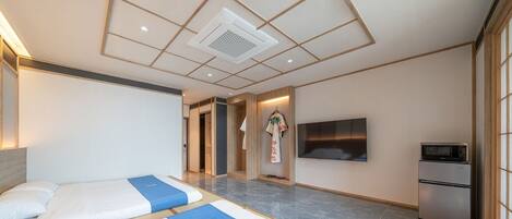 A hotel room with two beds, a flat-screen TV, a microwave, and a refrigerator.