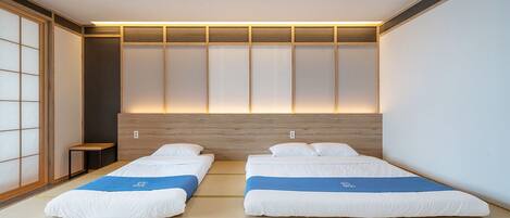 A modern hotel room with two beds, a wooden headboard, and a traditional tatami mat floor.