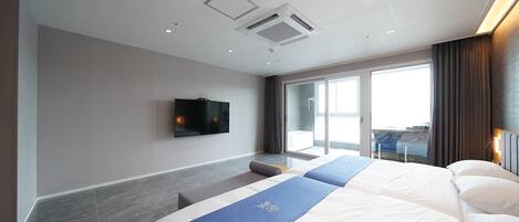 Una habitación de hotel moderna con una cama grande, un televisor de pantalla plana en la pared y un ventanal corredero que da a un balcón.