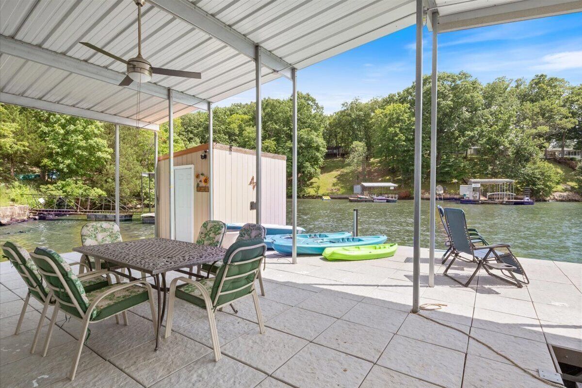 Un espace extérieur abrité, équipé d’une table et de chaises, un petit abri de jardin et des kayaks, le tout situé au bord d’un lac.