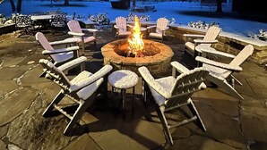 An outdoor seating area with a fire pit surrounded by snow-covered chairs and tables.