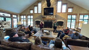 A spacious living room with a stone fireplace, leather couches, and large windows.