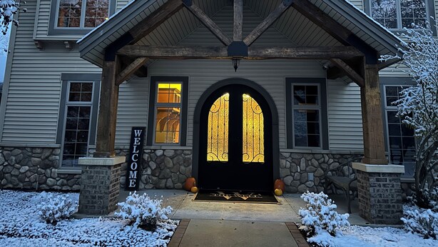 A two-story house with a stone foundation, a welcoming archway, and a "WELCOME" sign.