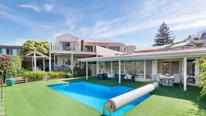 Ein Schwimmbecken mit integriertem Whirlpool, umgeben von einer überdachten Terrasse mit Sitzgelegenheiten.