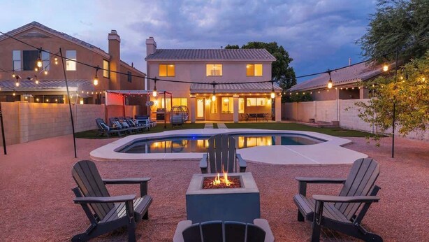 A house with a swimming pool, outdoor seating, and string lights.