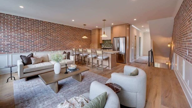 Una sala de estar moderna con pared de ladrillo, un comedor y una cocina.
