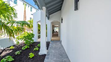 A covered pathway leading to a building with white walls and a tiled floor.