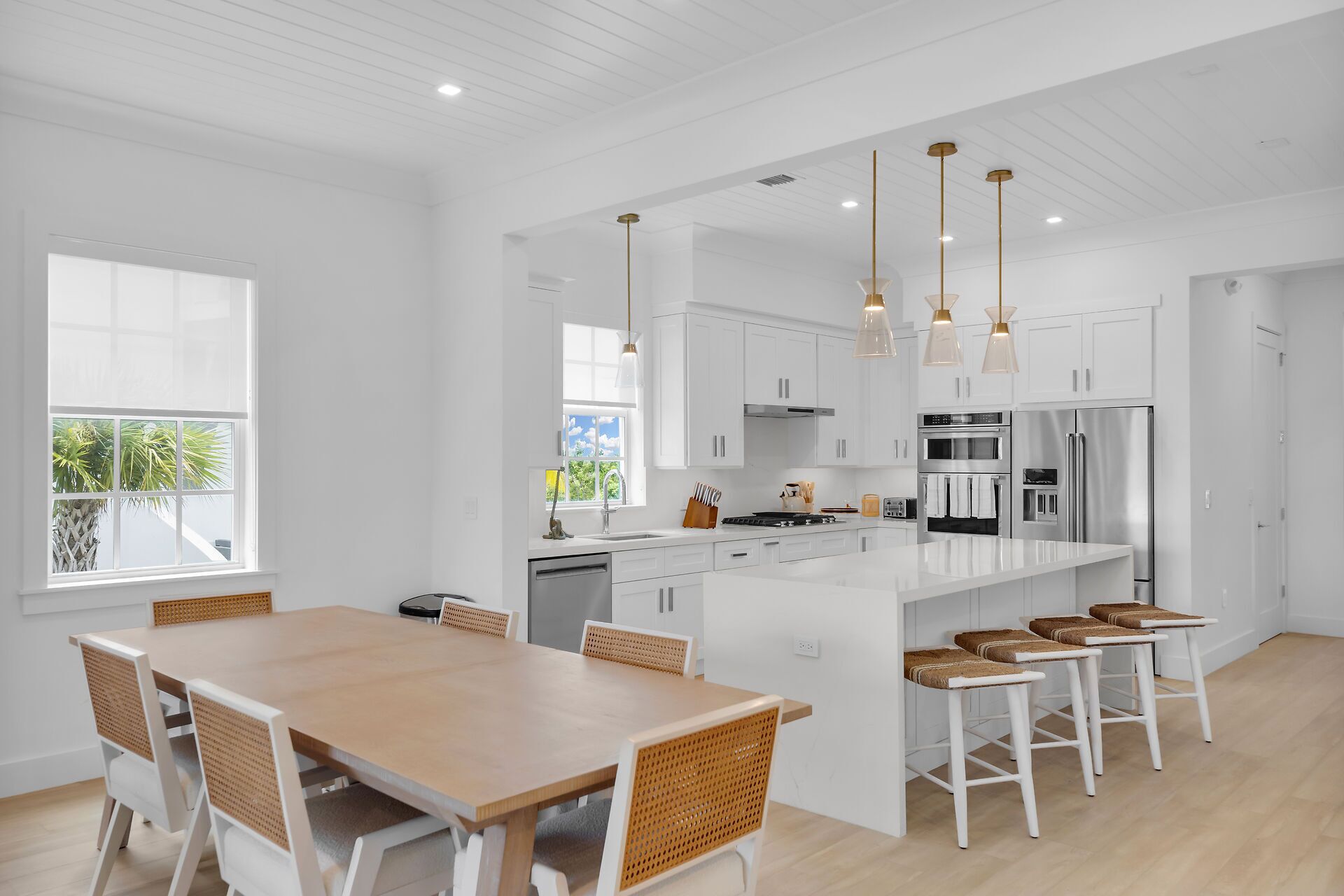 Una cocina moderna con armarios blancos, electrodomésticos de acero inoxidable y una isla central con taburetes de bar.