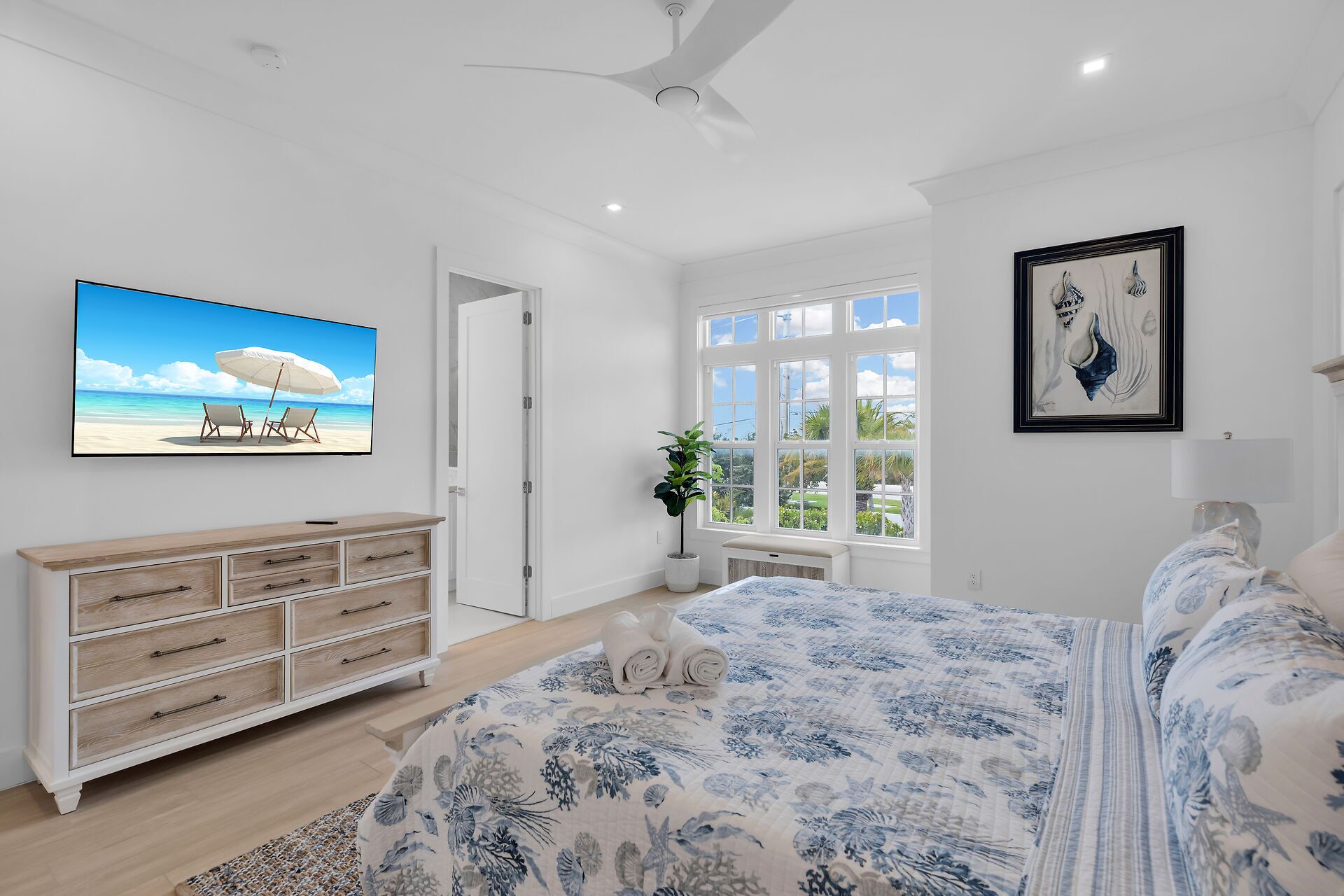 Une chambre à coucher avec un lit, une commode, un téléviseur, une fenêtre et une porte.