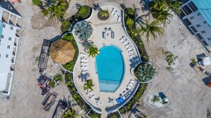 An aerial view of a resort with a central swimming pool, sun loungers, and palm trees. - Sea Glass Cove (Marathon)