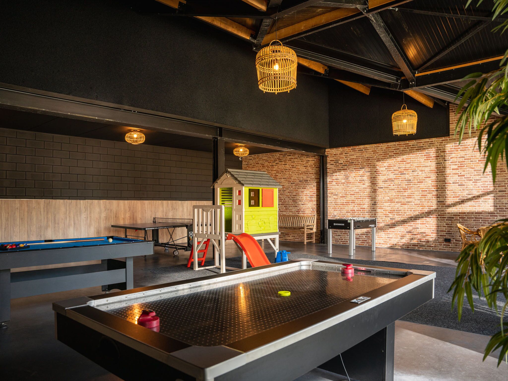 Una mesa de billar con bolas, una zona de juegos infantiles y un muro de ladrillo.