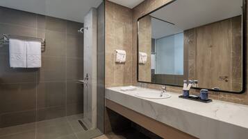 A modern bathroom with a shower, two sinks, a large mirror, and a towel rack with a towel labeled "ASTON".