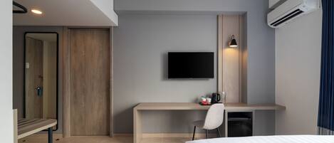 Habitación de hotel con dos camas, un escritorio con silla, un televisor de pantalla plana, cafetera y aire acondicionado.