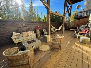 A wooden deck with outdoor furniture, including a sofa, chairs, and a fire pit. - 
Sunny boho retreat with deck & stylish hot tub (Santa Cruz)