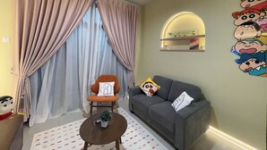 Una sala de estar con un sofá, un sillón, una mesita con una planta y una pared decorada con personajes de caricaturas.