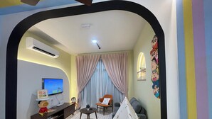 Una sala de estar con televisión, sofá y una mesita.