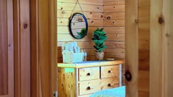 Une pièce en bois avec un lit, une commode et un miroir au mur.