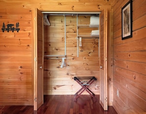 A wooden interior with a metal rack, a ladder, and a framed picture on the wall.