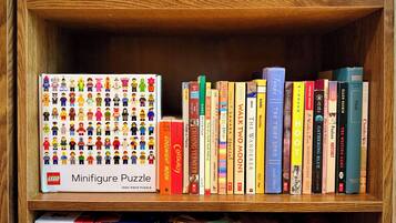 A bookshelf with a variety of books and a LEGO minifigure puzzle box.