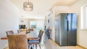 Une cuisine moderne avec un coin repas, un réfrigérateur en acier inoxydable et une vue sur l’extérieur.