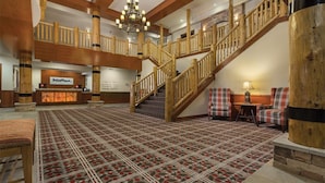 A spacious lobby with a checkered carpet, wooden staircase, and a reception desk. - Cozy 2-bedroom condo with WiFi, fitness room and pool close to the park entrance (West Yellowstone)