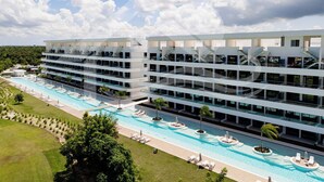 Un hôtel à plusieurs étages doté d’une piscine, d’un espace extérieur aménagé et offrant une vue sur un ciel dégagé.