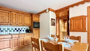 Une cuisine en bois avec un dosseret carrelé, des placards en bois et une table à manger pour quatre personnes.